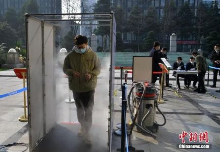 2月11日，成都市高新区吉泰路附近一办公楼，一男子登记、测体温和消毒后进大楼。中新社记者 刘忠俊 摄