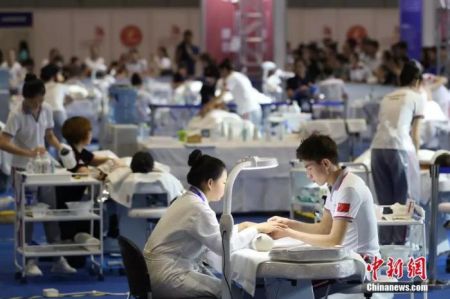资料图：2018中国技能大赛现场，美容师正在给体验者做指甲。 张亨伟 摄