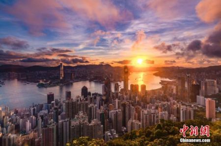 　2020年6月30日早晨，一阵骤雨过后，笼罩在香港上空的乌云逐渐消散，一轮朝阳在东方喷薄而出，曙光照耀维港两岸。中新社记者 张炜 摄
