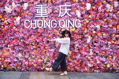 图为嘉宾在重庆观音桥商圈“鲜花墙”前打卡。