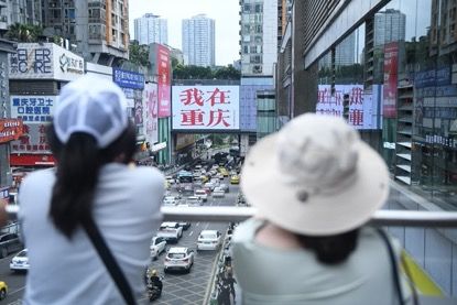 图为游客在重庆观音桥商圈“我在重庆”大屏幕前拍照。