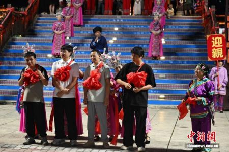 7月23日晚，四川省达州市宣汉县巴山大峡谷上演了一场传统土家婚俗秀。这场表演秀以传统土家婚嫁为题材，融合钱棍、唢呐、锣鼓、高跷、竹伞、绸扇、车灯等传统民间文艺样式，吸引不少游客沉浸式体验传统土家婚俗魅力。图为游客体验传统土家婚俗秀。中新社记者 张浪 摄