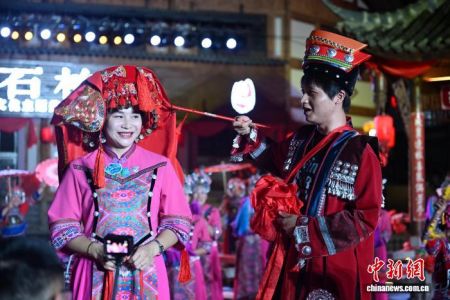 图为传统土家婚俗秀现场，“新郎”挑盖头。中新社记者 张浪 摄