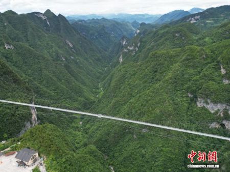 7月24日，参加“行走中国·2025海外华文媒体川渝行”活动的20余家海外华文媒体代表走进四川省达州市宣汉县巴山大峡谷，体验跨度680米、落差380米的玻璃桥。图为群山中的玻璃桥。(无人机照片)中新社记者 张浪 摄