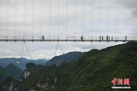 　　7月24日，参加“行走中国·2025海外华文媒体川渝行”活动的20余家海外华文媒体代表走进四川省达州市宣汉县巴山大峡谷，体验跨度680米、落差380米的玻璃桥。图为海外华文媒体代表在玻璃桥上打卡。中新社记者 张浪 摄