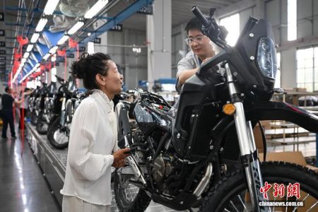 图为一位海外华媒代表在生产车间与摩托车生产线工人交流。中新网记者 何蓬磊 摄 图为一位海外华媒代表在生产车间与摩托车生产线工人交流。中新网记者 何蓬磊 摄