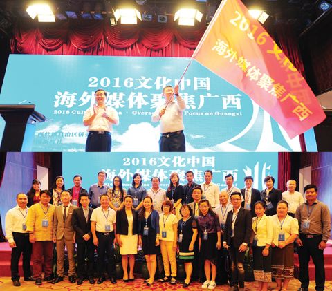 室主任秦春成(左)向海外媒体代表,柬埔寨《金边晚报》总编辑李翼授旗