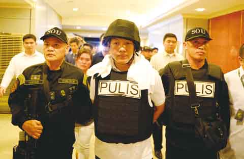 圖為韓國商人綁架撕票案中其中一名嫌犯仙沓伊沙迷警員（中）昨天被警員押送離開岷里拉市國調局。（法新社）