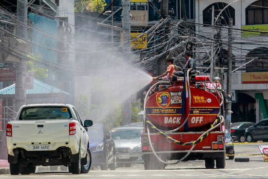 圖為一輛消防車在馬尼拉街頭噴灑消毒水。（新華社）