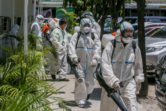 4月7日，在菲律賓馬尼拉，一名工作人員在一家醫院外進行消毒工作。為了更好防控疫情，菲律賓政府7日決定將首都馬尼拉所在的呂宋島的社區隔離政策延長至4月30日。（新華社）
