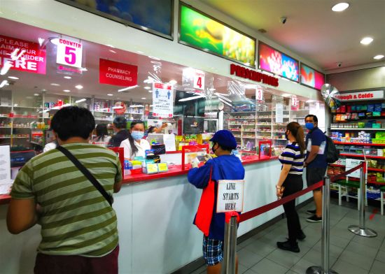 5月16日是大岷區結束62天的「加強社區隔離」，進入15天「改良版加強社區隔離」的首日，馬加智的綠帶商圈，銀行、藥店、生活超市開始正常對外營業，部分餐廳開始外賣。菲政府要求民眾在公共場合做好個人防護，保持社交距離。圖為著名的連鎖藥店水星藥房開始營業，店家在收銀員與顧客之間掛起了塑料薄膜簾，預防病毒傳染。（中新社）
