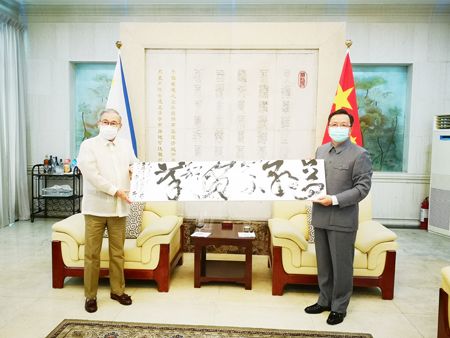 外長陸辛（左）與中國駐菲大使黃溪連（右）共同慶祝即將到來的中華人民共和國成立71周年和中秋佳節，並就雙邊關係交換看法。圖為黃溪連向陸辛贈送使館館員書寫的書法作品《只爭朝夕，不負韶華》。（中國大使館供圖）