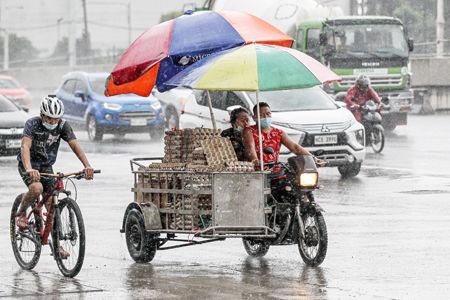 圖為馬尼拉市民昨日出行時，遇到因颱風謹沓帶來的傾盆大雨和洪澇。（新華社）