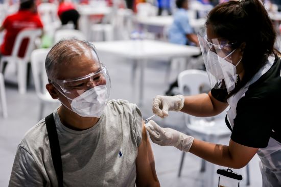 一名戴著防護口罩的居民4月1日在仙範市改造成疫苗接種地點的體育場館內接受新冠疫苗。(新華社)