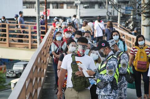 圖為警方昨日在計順市羅斯福巴士車站檢查排隊等候乘車的乘客身份證件。根據政府的封城規定,只有獲准外出的人士才能出行。