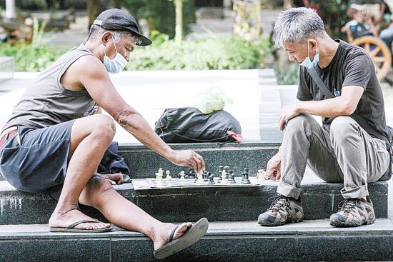 兩名乘客昨日在馬尼拉市文尼法壽廣場等待前往甲美地省的巴士時，玩國際象棋打發時間。