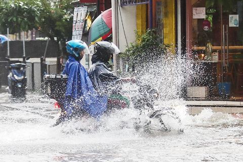 7月19日，計順市，民眾騎摩托車通過積水的道路。熱帶風暴「克里星」在離開菲律濱時增強為強烈熱帶風暴，為許多地區帶來強風和豪雨。（新華社）
