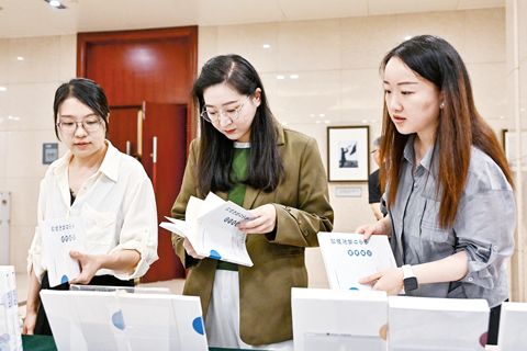 8月21日,與會者在北京舉行的「南海真相」系列智庫報告發佈暨南海問題研討會現場翻閱「南海真相」系列智庫報告。(新華社)