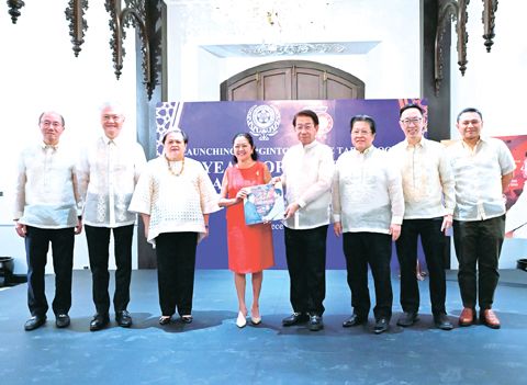 12月1日，由菲華商聯總會編纂的紀念畫冊《金：菲律濱與中國建交五十年》在馬尼拉市歷史建築戈爾登伯格別墅舉行隆重的發佈會。圖為商總理事長林榮輝呈送紀念畫冊給第一夫人莉莎．亞蘭禮沓——馬科斯。左起為商總新聞委員會共同主任許贊逢、執行副理事長黃奇昭、外交部長拉扎羅、第一夫人莉莎．亞蘭禮沓——馬科斯、理事長林榮輝、名譽理事長施東方、新聞委員會共同主任李天榮和教育部長洪雅拉。（王偉祥攝）