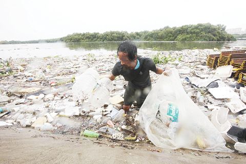 一名男子8月16日在巴蘭玉計市海岸線收集塑膠瓶。他可以將這些可回收材料以每公斤10披索的價格出售。