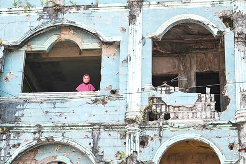 在這張攝於2026年9月8日的照片中，索拉婭·坦博從她在南蘭佬省馬拉威受損的房屋窗戶向外眺望。（法新社）