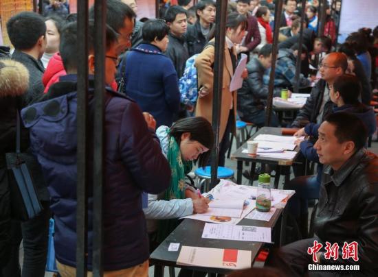 资料图：在武汉市纳杰人才市场招聘会上，挤满了前来应聘的求职者。中新社记者