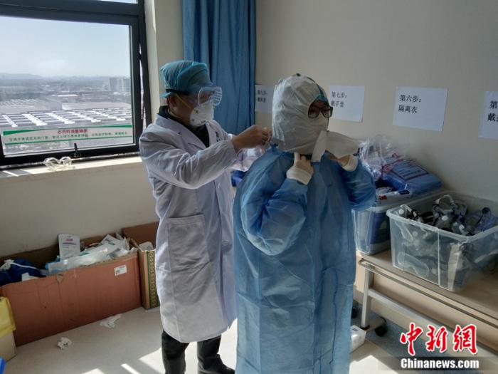 武汉协和医院麻醉科主任陈向东教授为胡晓敏教授整理防护服。受访人供图