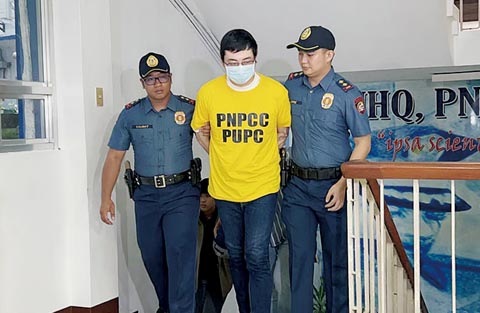 中國籍殺人犯及綁匪頭王丹煜（黃衣者）昨日被押解到克楠美軍營展示給記者。