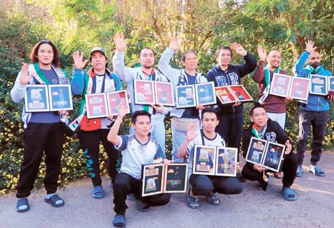 這張12月3日的視頻截圖顯示，在也門首都薩那國際機場，被釋放的船員在登機前手持紀念品合影。（新華社）