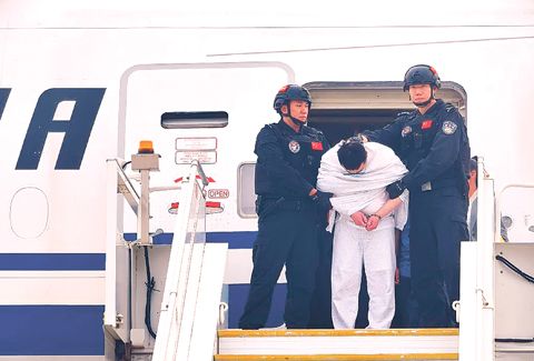 7月20日,在北京首都國際機場,在境外針對中國公民實施綁架殺人犯罪的主要犯罪嫌疑人劉某文在警方押送下走出機艙。(新華社)