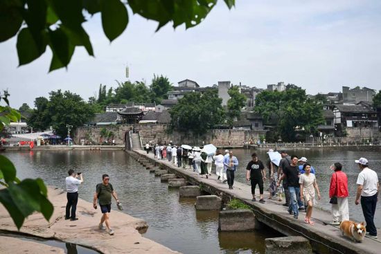 6月14日,游客在万灵古镇大荣桥上游玩。中新社记者