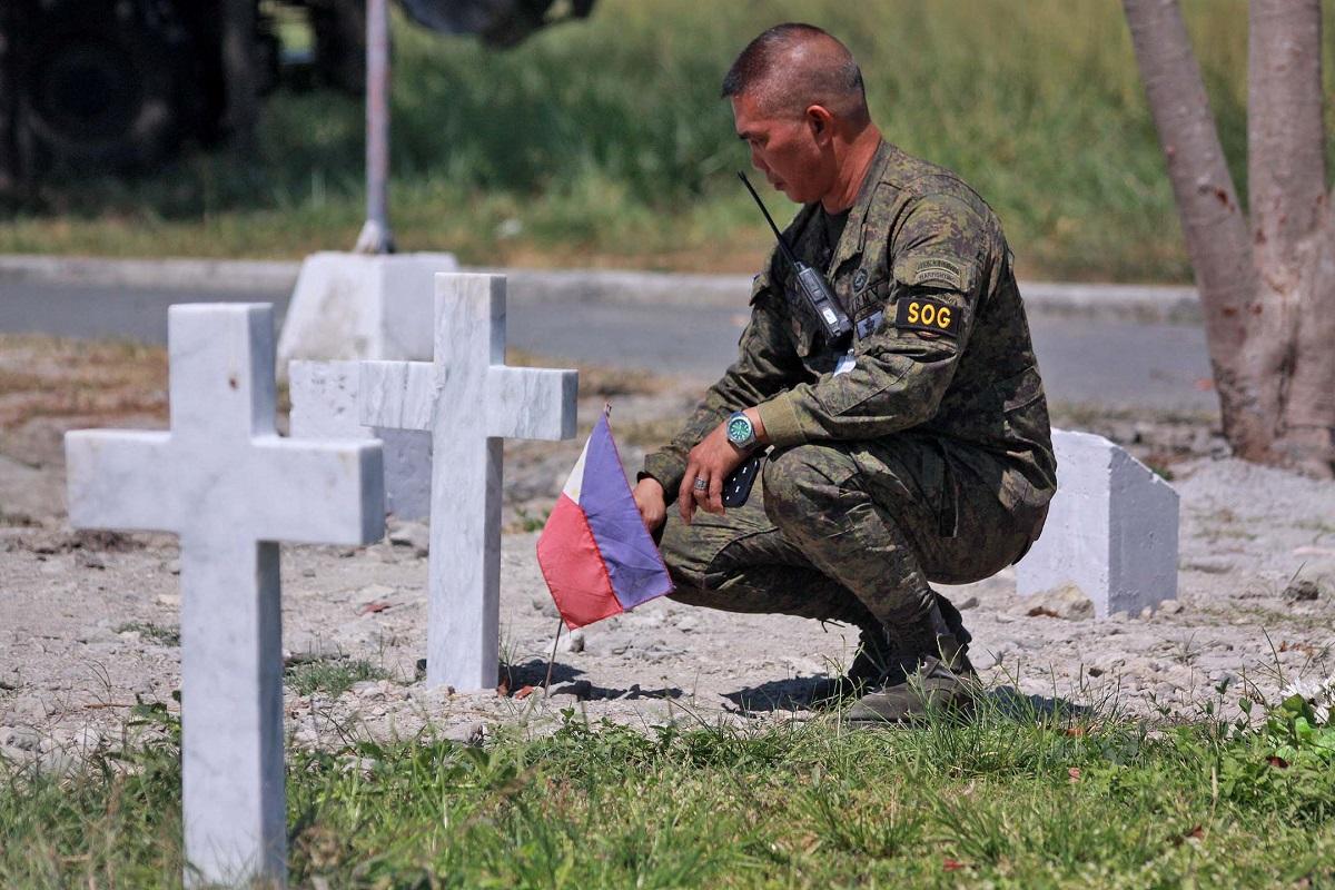 在「英勇日」前夕，一名菲陸軍士兵在英雄墓園為在二戰中喪生的親屬墓前放置國旗。